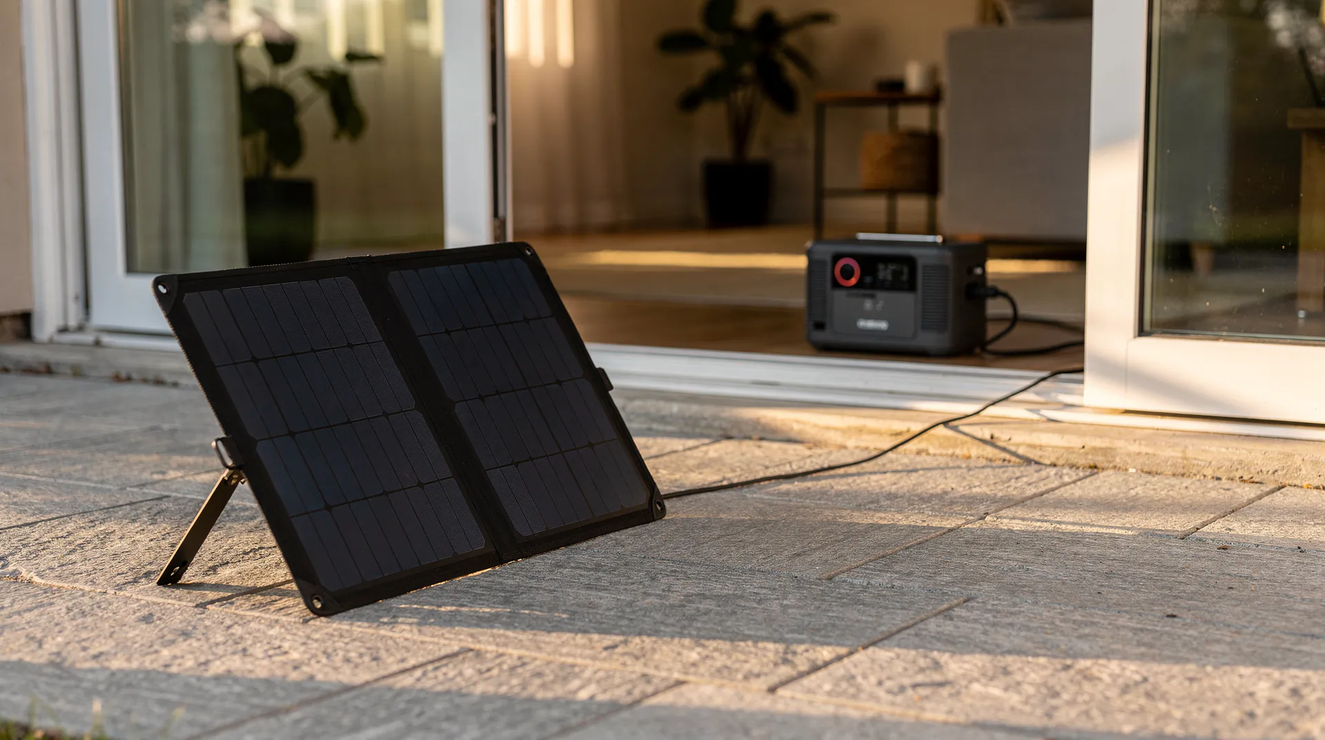 Station d'énergie portable connectée à un panneau solaire pliable sur la terrasse d'une maison